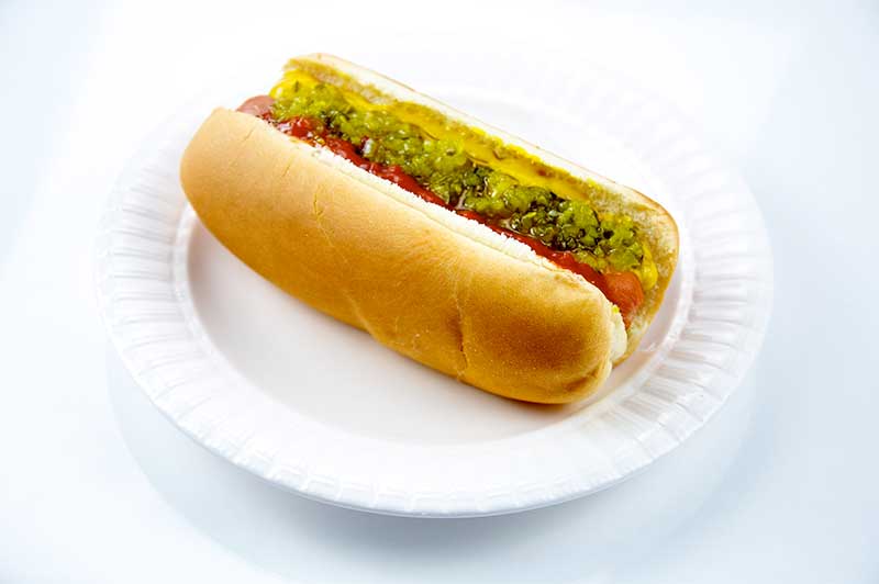 Hot dog on bun with mustard and relish