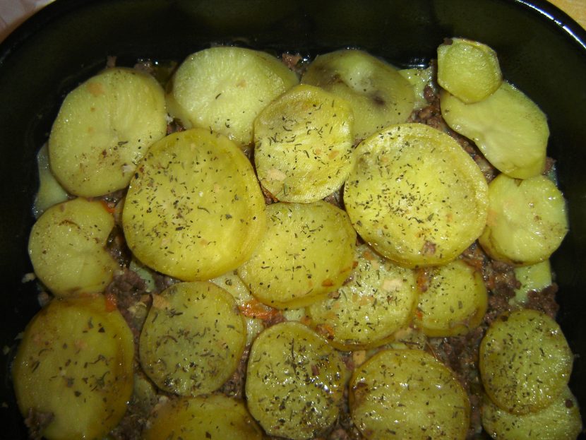 A baked moussaka casserole with a layer of sliced potatoes and savory meat filling